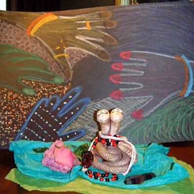 hotel room shrine with painting, statue, flowers, crystals and beads